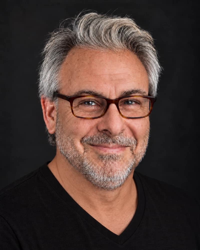Jack Skates in a black V-neck T-shirt and tortoiseshell glasses.